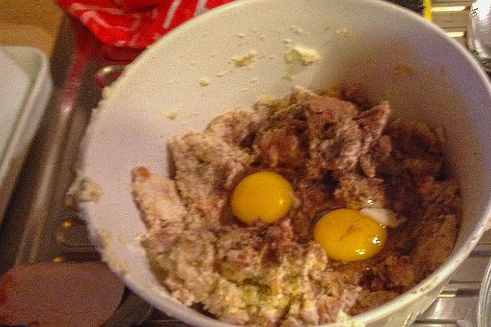 Während der Spinat köchelt, altes Brot in Würfel schneiden und mit Milch, 2 Eiern, Salz, Pfeffer und Muskatnuss vermengen