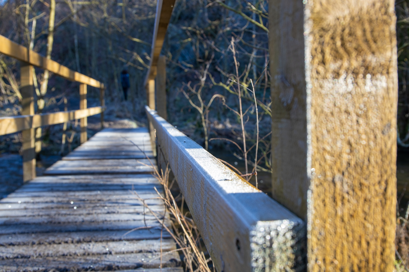 Durch den Reif schlüpfriges Holz der Brücke