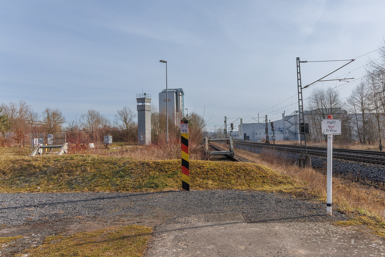 DDR-Grenzsäule und ein Beobachtungsturm im Hintergrund